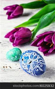 Decorated with painted Easter eggs and flowers on a light background. Easter composition with flowers