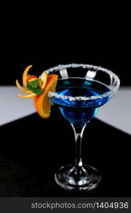 Decoration for a cocktail of orange and mint. Elegant and original presentation. Martini Blue Curacao on a black background