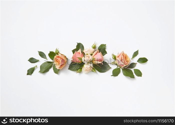 Decoration from beautiful roses flowers with green leaves on a light grey background, copy space. Congratulation card for birthday.. Greeting card with blooming coral roses flowers.