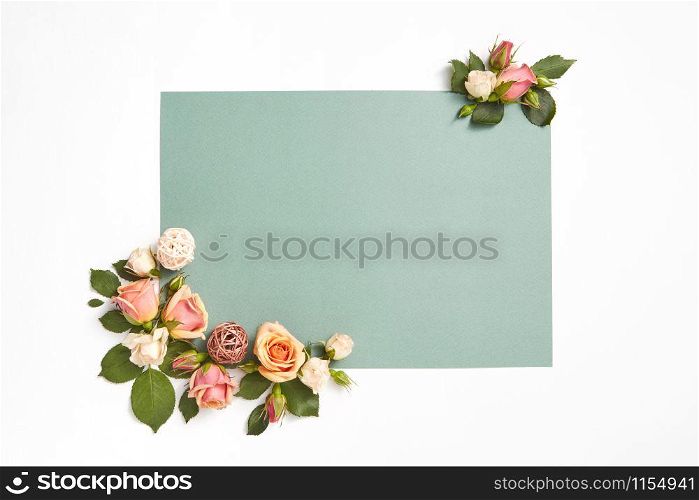 Decoration from natural blossoming roses flowers with green leaves on a light grey background, copy space. Congratulation card for birthday.. Corner greeting card with roses flowers and leaves.