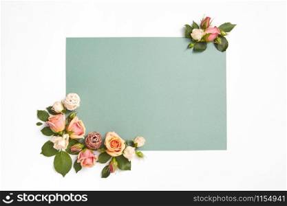 Decoration from natural blossoming roses flowers with green leaves on a light grey background, copy space. Congratulation card for birthday.. Corner greeting card with roses flowers and leaves.
