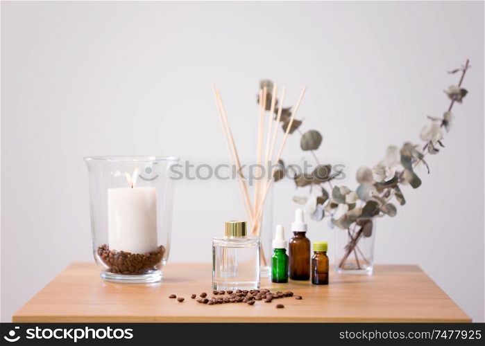 decoration, home perfume and aromatherapy concept - aroma reed diffuser, burning candle and essential oil on table at home. aroma reed diffuser, candle and essential oil