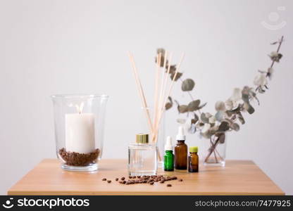 decoration, home perfume and aromatherapy concept - aroma reed diffuser, burning candle and essential oil on table at home. aroma reed diffuser, candle and essential oil