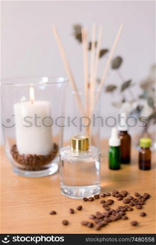 decoration, home perfume and aromatherapy concept - aroma reed diffuser, burning candle and essential oil on table at home. aroma reed diffuser, candle and essential oil