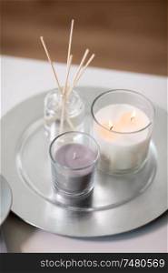decoration, hygge and aromatherapy concept - aroma reed diffuser an candles burning on tray. aroma reed diffuser an candles burning on tray