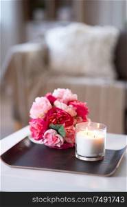 decoration, hygge and cosiness concept - burning fragrance candle and flower bunch at cozy home. burning fragrance candle and flower bunch at home