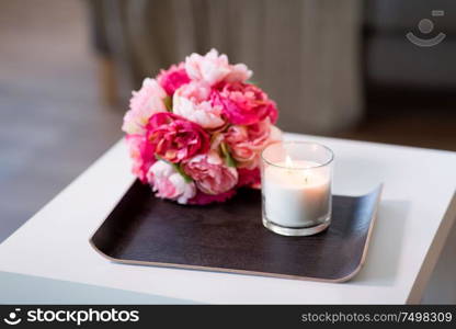 decoration, hygge and cosiness concept - burning fragrance candle and flower bunch at cozy home. burning fragrance candle and flower bunch at home