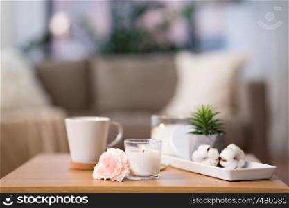 decoration, hygge and cosiness concept - burning fragrance candle and flower bunch on wooden table. burning candle and flower bunch on wooden table