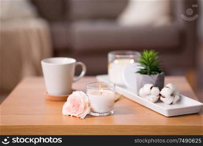 decoration, hygge and cosiness concept - burning fragrance candle and flower bunch on wooden table. burning candle and flower bunch on wooden table