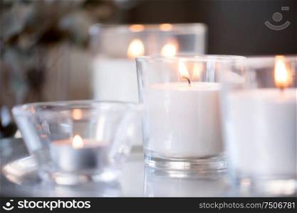 decoration, hygge and cosiness concept - burning white fragrance candles on table. burning white fragrance candles on table