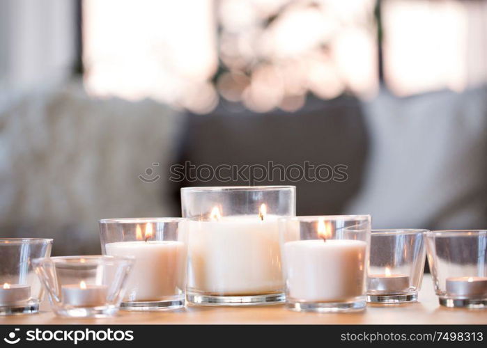 decoration, hygge and cosiness concept - burning white fragrance candles on table at home. burning white fragrance candles on table at home