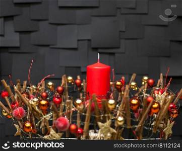 decorative balls and stars decorated gold color red candle on a dark background with tiles for the new year. Christmas decorative candle decorated