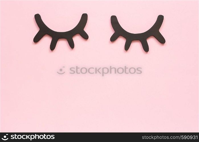 Decorative black wooden eyelashes, closed eyes on pink background. Concept Good night or Sweet dreams Greeting card Top view Copy space Template for lettering, text or your design.. Decorative black wooden eyelashes, closed eyes on pink background. Concept Good night or Sweet dreams Greeting card Top view Copy space Template for lettering, text or your design