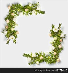 Decorative blossoming corner frame from evegreen leaves banches and little flowers on a light grey background with copy space. Flat lay. Valentine&rsquo;s Day concept.. Square corner frame from boxwood twigs and flowers.