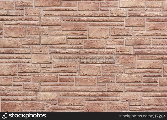 Decorative brick wall as background or texture. Artificial stone in the brown hues in geometric pattern.