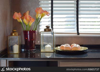 decorative candle set with brass glass lamp and beautiful flowers on the table at home