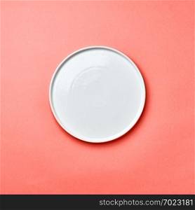 Decorative ceramic handmade empty white plate presented on a background in color of the year 2019 Living Coral pantone with copy space for your menu. Can be used for montage your products. Top view.. Porcelain empty round handmade a plate on a background in color of the year 2019 Living Coral pantone with a copy of space. Flat lay