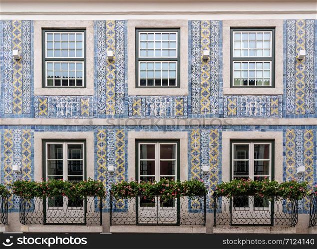 Decorative ceramic tiles on a large house with balconies in downtown Lisbon, Portugal. Traditional ceramic tiles decorate exterior of large house in Lisbon