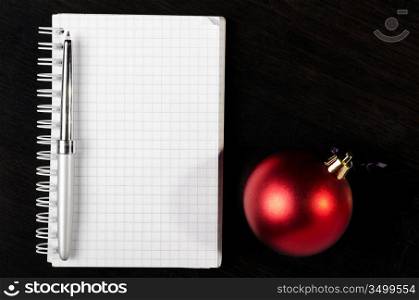 decorative christmas ball with notepad on dark table