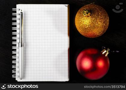 decorative christmas ball with notepad on dark table