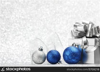 Decorative Christmas balls and gift on silver bokeh background