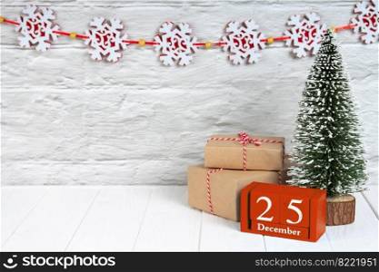 Decorative Christmas tree, gift boxes with in craft paper and red wooden perpertual calendar with date on white wooden background. Banner, header, New Year background with copy space
