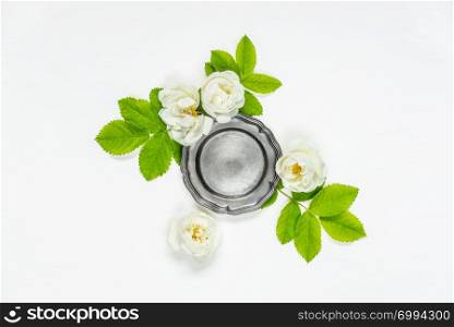 Decorative composition in retro style consisting of vintage metal tray ore retro plate and white rose flowers with green leaves on white background. Top view, flat lay