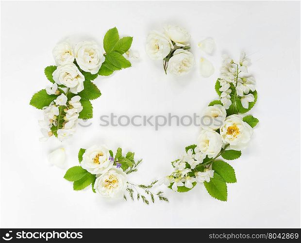 Decorative composition in retro style consisting of white wild rose and white locust flowers with green leaves on white background. Top view, flat lay