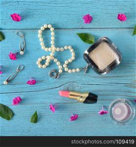 Decorative cosmetics and jewelry made of pearls on an old wooden background of blue color. Flat lay, top view. Free space for text.