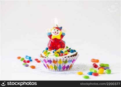 decorative cup cake with illuminated clown candle white background
