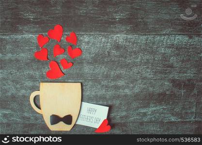Decorative Cup with bow-tie and hearts on wooden background. Fathers day concept. Decorative Cup with bow-tie and hearts on wooden background. Copyspace.