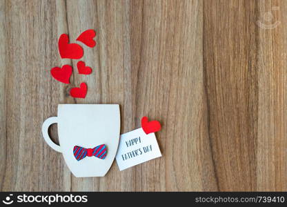 Decorative Cup with bow-tie and hearts on wooden background. Greeting card. Fathers day concept. Decorative Cup with paper bow-tie and hearts on wooden background. Copyspace.