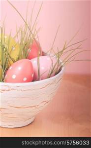 Decorative eggs in pot with grass over pink background. Easter decor.. Easter decor