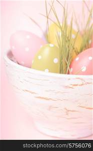 Decorative eggs in pot with grass over pink background. Easter decor.. Easter decor