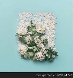 Decorative floral layout made of white flowers, petals and blossom on pastel blue background. Spring and summer concept. Flat lay, top view. Invitation or card for wedding, birthday and other holiday