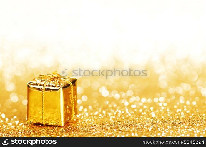 Decorative golden box with holiday gift on shiny glitter background
