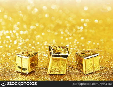 Decorative golden boxes with holiday gifts on shiny glitter background