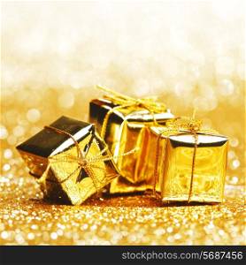 Decorative golden boxes with holiday gifts on shiny glitter background