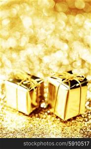 Decorative golden boxes with holiday gifts on shiny glitter background