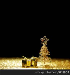 Decorative golden toy christmas tree and gifts on black background