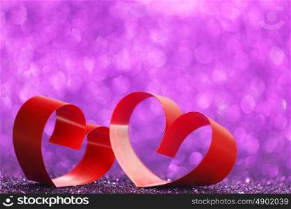Decorative hearts of red ribbon on shiny glitter background