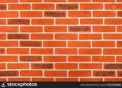 Decorative orange wall surface with horizontal imitation of brickwork with neat beige cement joints. Copy space.. Wall texture with a decorative finish that imitates the surface of orange brickwork with beige cement joints.