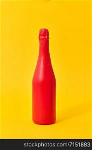 Decorative painted red wine bottle mock up on an yellow background with copy space. Minimal concept.. Red painted spray mockup bottle on an yellow background.