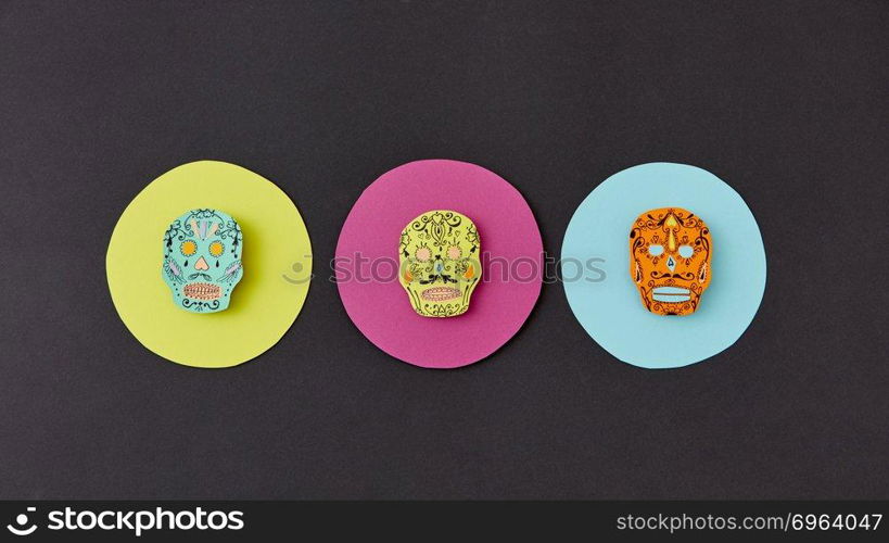 Decorative pattern from round frames with creative handmade skulls on a black paper background. Flat lay. Calaveras simbol of the Mexican holiday of Calaca. Flat lay. Colorful creative Calaca pattern handcraft from colorful round paper with decorative skulls on a black background.
