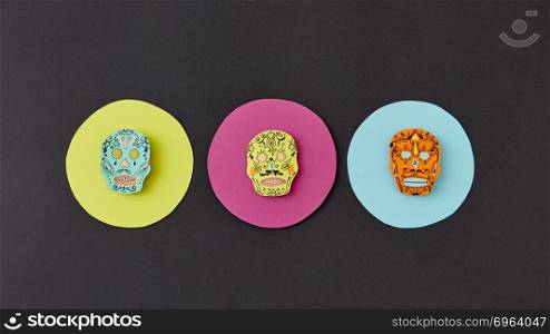 Decorative pattern from round frames with creative handmade skulls on a black paper background. Flat lay. Calaveras simbol of the Mexican holiday of Calaca. Flat lay. Colorful creative Calaca pattern handcraft from colorful round paper with decorative skulls on a black background.