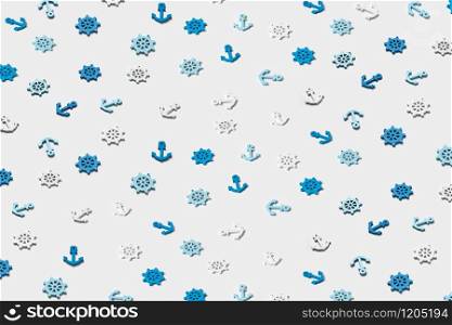 Decorative pattern from ship&rsquo;s marine symbols plastic anchors and steering wheels on a light grey background.. Pattern from small marine symbols with shadows.