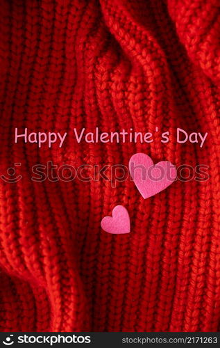 Decorative pink heart on a red knitted background, top view. Lettering Happy Valentine&rsquo;s Day. Decorative pink heart on a red knitted background, top view. Lettering Happy Valentine&rsquo;s Day.