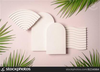 Decorative plaster podiums with palm leaves on pastel pink background, top view, flat lay. Place for product presentation. Creative product platform. Decorative plaster podiums