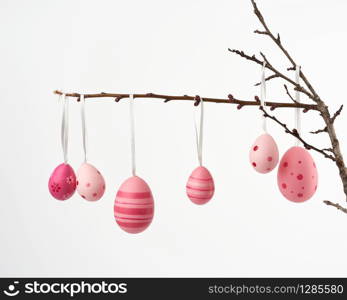 decorative plastic pink easter egg hanging on a branch, decor on a white background