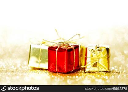 Decorative red and gold boxes with holiday gifts on shiny glitter background
